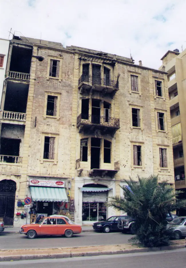 Our turn-of-the century apartment house on Beirut's Green Line in Ashrafieh. We lived on the fourth floor. My room was the second window from the right. Snipers perched atop the building, drawing fire. The round hole to the left of the floor is a direct rocket hit. Click on the image for larger view. (© FlaglerLive)