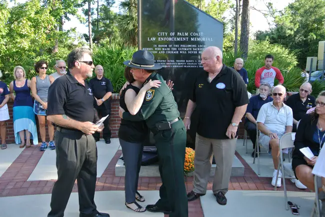 Flagler County Sheriff Jim Manfre embraces Frankie Celico's mother, with Frankie's father, Carlo, to the left, and Palm Coast Mayor Jon Netts to the right. 