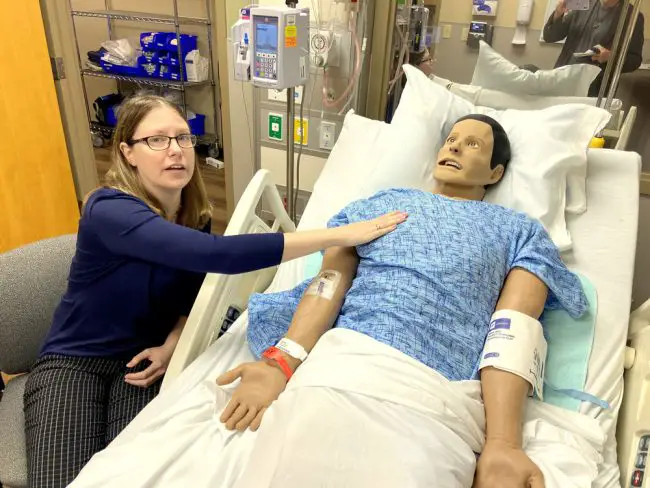April Whaley, a Flagler County actor who has performed with City Repertory Theater and Flagler Playhouse, also plies her trade at the Regional Simulation Center at AdventHealth Palm Coast. Here she’s seen by the bedside of her “husband,” Bill. (© FlaglerLive)