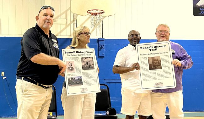 Bunnell Commissioner David Atkinson, Mayor Catherine Robinson, City Manager Alvin Jackson and Vice Mayor John Rogers hold the Bunnell History Trail signs that will be installed this month. FlaglerLive photo