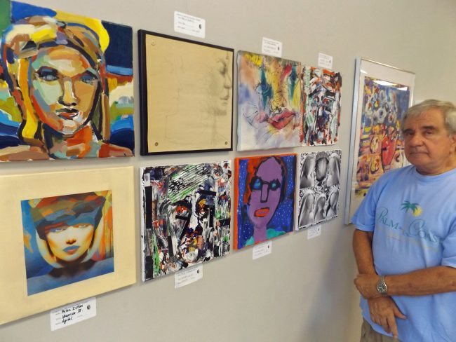 Tom Gargiulo, one of Palm Coast's most generous art patrons and an artist in his own right,  observes the paintings created as part of the 'head' assignment during a recent  workshop for area professional artists. The paintings are part of the 'Work”'exhibit at the Flagler County Art League in Palm Coast. . Click on the image for larger view. (© FlaglerLive)