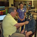 RN & School Health Coordinator Stephanie Ear looks on as an optometrist from Florida Heiken screens a student.