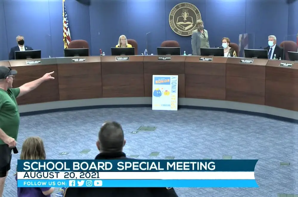 John Wilson, who opposes mask mandates, shouts at Sarasota County School Board chair and former state Rep. Shirley Brown (standing), who called a recess to clear the room of hecklers. (Sarasota County School Education Channel)