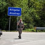 A Florida Highway Patrol officer looks on as protesters gather to demand the closure of the immigrant detention center known as "Alligator Alcatraz" at the Dade-Collier Training and Transition Airport in Ochopee, Florida, on July 22, 2025.