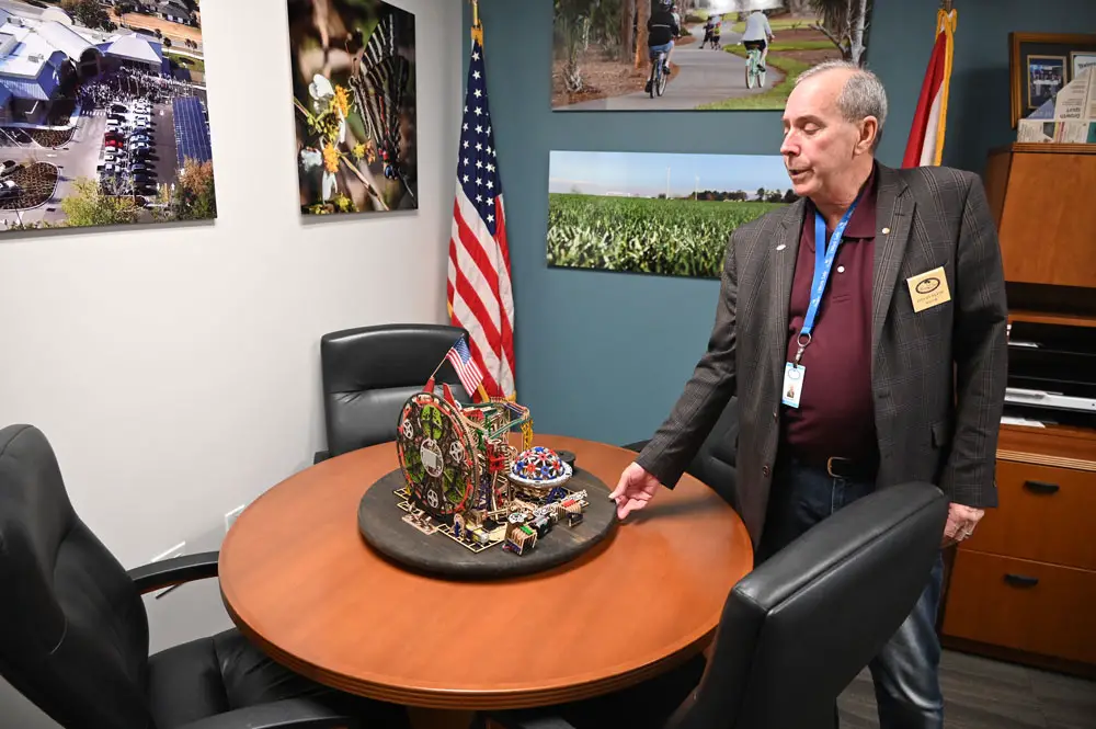 Palm Coast Mayor David Alfin in his office at City Hall, with a mechanical contraption made of as many parts as there are city employees. It wasn't working just then, perhaps aware that Alfin may not be there to oil it much longer. (© FlaglerLive)