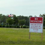 A no-trespassing sign on Allete-owned Town Center property near Central Park and City Hall. The sign may be gone within a few months should the city buy all Allete parcels and settle a lawsuit with the company. The sign is incorrect: willful trespassing is only a misdemeanor unless an individual is armed and has ill intent. (© FlaglerLive)