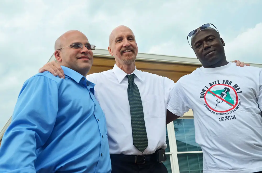 Seth Penalver, left, was on death row for almost 19 years before his exoneration and release in 2013. Herman Lindsay, right, was exonerated several years ago before Penalver. They are seen here with Mark Elliott, who heads Floridians for Alternatives to the Death penalty. (© FlaglerLive)