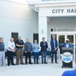 City Manager Alvin Jackson at the lectern, proclaiming "another great day in Bunnell," with all five members of the City Commission, the builder and a pastor this morning at the building's dedication. (© FlaglerLive)