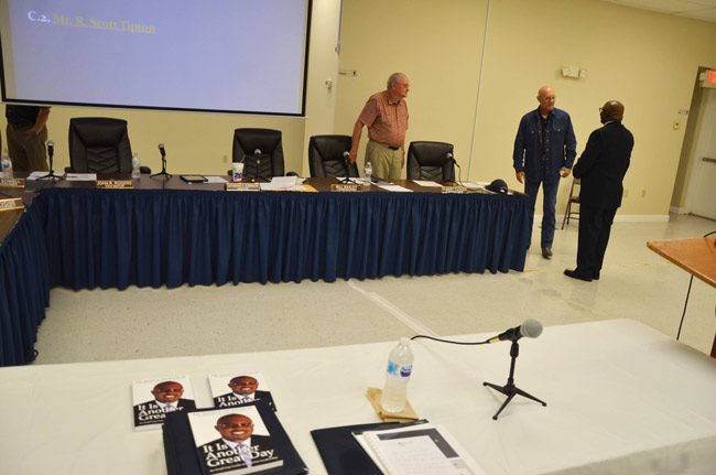 Manager candidate Alvin Jackson had laid out copies of his self-published book, 'It Is Another Great Day,' before his interview Tuesday, and distributed copies to commissioners. He spoke with Commissioners Bill Baxley, left, and Elbert Tucker. (© FlaglerLive)