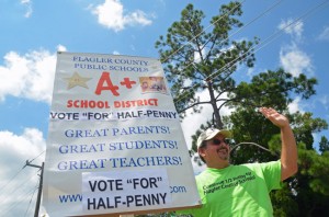 Andy Dance, the Flagler County School Board member, was the tireless point man in the effort to renew the half-cent sales tax for Flagler schools. He was waving for the cause under a midday sun at the intersection of Belle Terre and Palm Coast Parkway today. (© FlaglerLive)