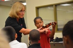 Angelina Descartes gets her first touch of a violin with Sue Cryan at Rymfire Elementary. Click on the image for larger view. (© FlaglerLive)