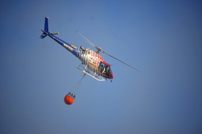Fire Flight, the county's emergency helicopter, with its Bambi Bucket fighting a fire in 2015. (© FlaglerLive)