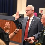 Derek Barrs as he was sworn-in at the School Board by County Judge Melissa Distler, alongside Sheriff Rick Staly, last November. (© FlaglerLive)
