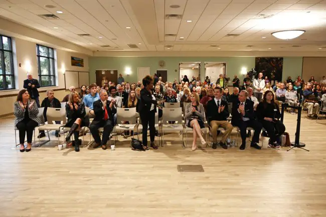 Characteristically unassuming, Denise Bevan, far left, was as if literally at the edge of last February State of the City address at the Palm Coast Community Center. Council members and the mayor filled most of the front-row seats. (© FlaglerLive)
