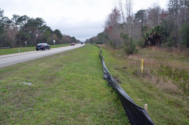 The bike may have been airborne until it fell just past the black construction fence and tumbled into the ditch. Click on the image for larger view. (© FlaglerLive)