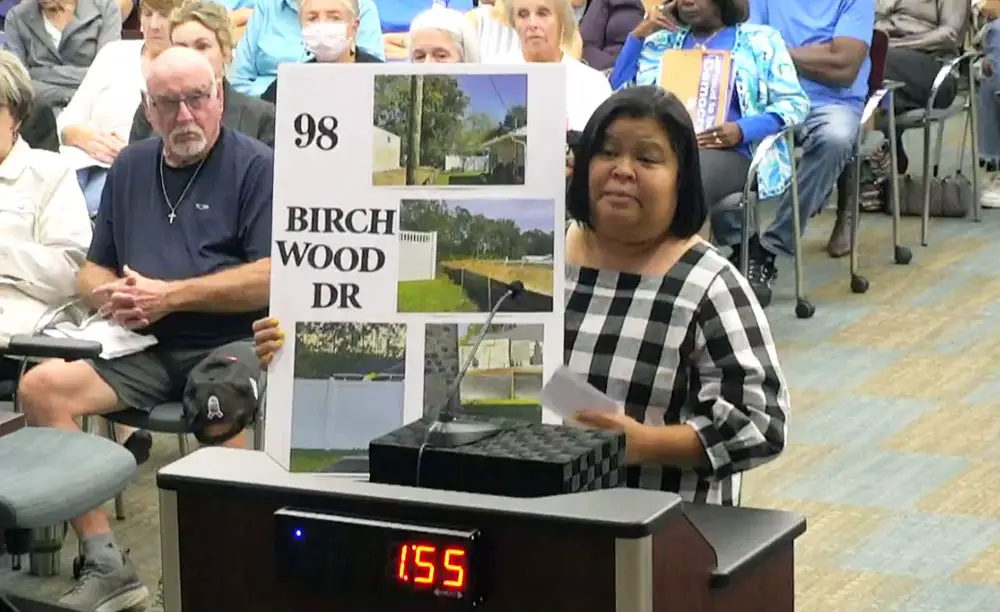 Mara Wuerth brought a visual aid to show Palm Coast City Council members the sharp difference in heights between her lot and the new fill for a house next door under construction. (© FlaglerLive via Palm Coast TV)