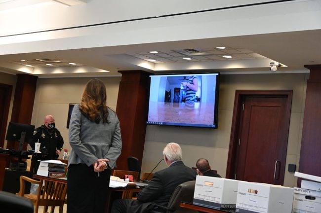 Brandi Celenza in her last moments alive, in a clip shown to the jury in court today. Keith Johansen watches, at the far right. Assistant State Attorney Jennifer Dunton is standing to the left. (© FlaglerLive)
