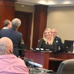 Brenna Cronin, one of four Drug Court graduates at Thursday's ceremony, as she addressed the audience while Retired Judge Terence Perkins held her son. (© FlaglerLive)