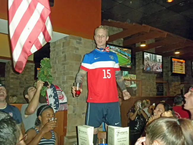 Brian Bennet, a graduate of Matanzas High School, where he played soccer, lead the cheers at Houligan's in Palm Coast during the U.S.-Ghana match. (© FlaglerLive) 