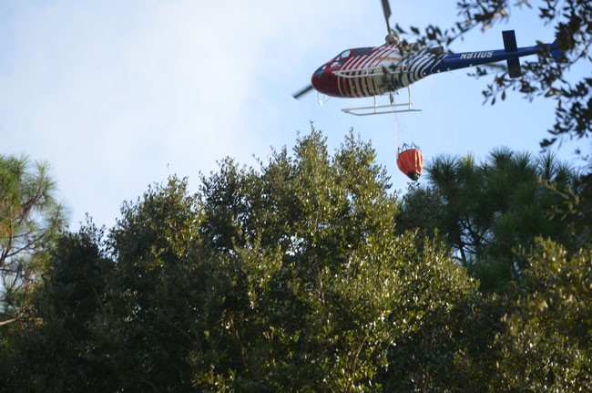 Flagler County Fire Flight was dropping water buckets on the fire this afternoon, keeping it under control until firefighters could get to it. (c FlaglerLive)