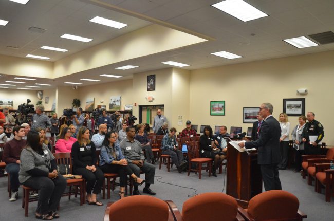 There was something surreal about the news conference setting, in a middle school library, when superimposed on its theme and subject matters. Click on the image for larger view. (© FlaglerLive)