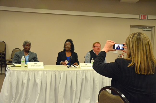 Rebecca DeLorenzo, president of the Flagler County Chamber of Commerce, takes a measure of one of the candidates just before the forum the chamber organized ahead of the March 4 elections to the Bunnell City Commission. The candidates from left: Daisy Henry, Bonita Robinson and John Rogers. (© FlaglerLive)