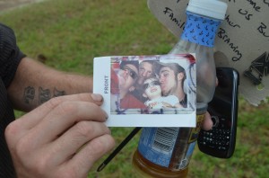 Corey Miller shows a recent family picture with Lane he'd brought to graveside. Click on the image for larger view. (© FlaglerLive)