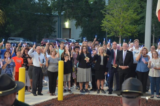 As each fallen officer's name was called, the crowd lifted its blue candles. Click on the image for larger view. (© FlaglerLive)