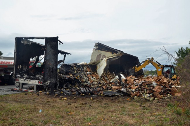 To ensure that the fire would not start again, a backhoe demolished what remained of the trailer hauling tons of cantaloupe. Click on the image for larger view. (© FlaglerLive)