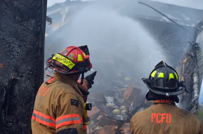 The Palm Coast Fire Department had to smother a brush fire before focusing on the trailer. Click on the image for larger view. (© FlaglerLive)