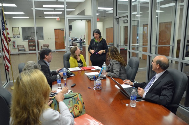 Kaiti Lenhart, at the head of the table, is the interim Supervisor of Elections for Flagler County, and was part of Monday's canvassing board meeting, with County Commissioner Nate McLaughlin to her left, and, to her right, County Judge Melissa Moore-Stens and County Attorney Al Hadeed. Standing was Maureen Baird, the operations manager at the Citrus County Supervisor of Elections' office. (© FlaglerLive)