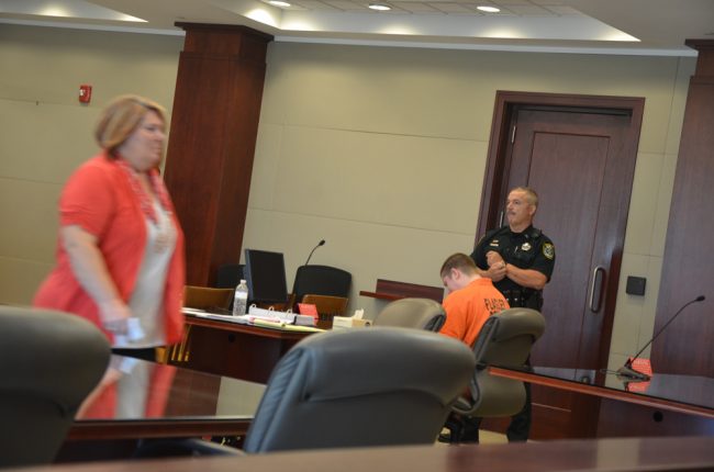 Carl Devore, seated, cried as his mother testified, and cried as she walked by him afterward, the closest she'd been to him since dropping him off at the Sheriff's Office 441 days ago, never to see him in person, or touch him, since. (c FlaglerLive)