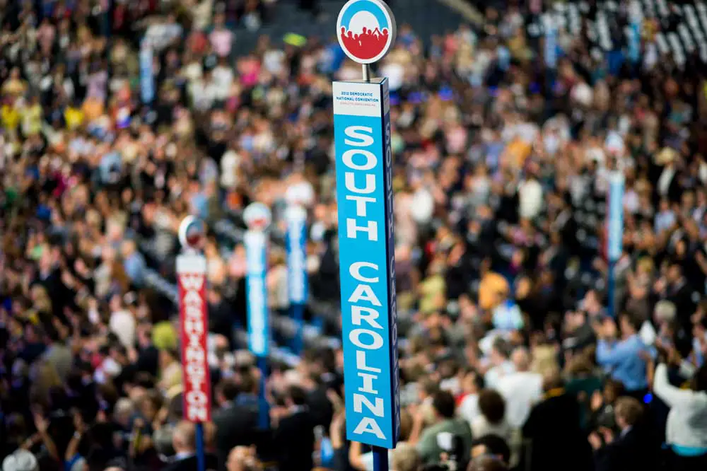 Caucusgoers stand beneath the sign for the South Carolina delegation at the Democratic National Convention.