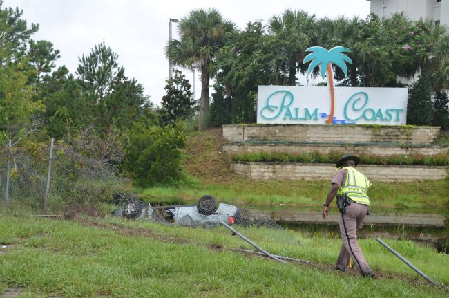 The Chevy Malibu flipped into the retention pond at the foot of the Days Inn, on the exit ramp off the southbound exit from I-95. Click on the image for larger view. (© FlaglerLive)