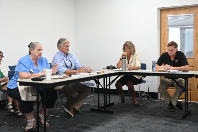 There were a lot of stony expression at the town commission meeting Thursday evening. From left, Town Manager Suzanne Dixon, Town Attorney Dennis Bayer, Town Commissioner Jessica Finch, and Mayor Douglas Dew, who goes by Dewey. (© FlaglerLive)