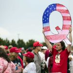 A protester holds a Q sign as he waits to enter a campaign rally with then-President Donald Trump in Wilkes-Barre, Pa., in August 2018.
