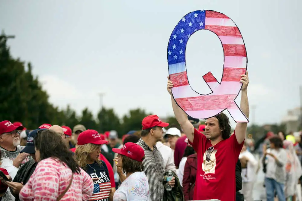 A protester holds a Q sign as he waits to enter a campaign rally with then-President Donald Trump in Wilkes-Barre, Pa., in August 2018. 