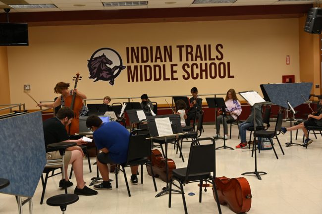 Conductor Niki Mousikos setting up before rehearsal with the Overture Orchestra in a corner of the Indian Trails cafeteria. (© FlaglerLive)