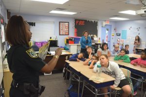 Flagler County Sheriff's corrections deputy Sheria Woods had been on duty 16 hours before coming to the read-in. Her students had no right to seem more tired than she was, particularly since she did not let on. Click on the image for larger view. (© FlaglerLive)