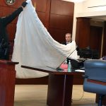 Flagler County Sheriff's detective Joe Costello and a bailiff showing the jury the comforter that was on the bed where the alleged assault took place a June night in 2019, in Palm Coast's P Section. (© FlaglerLive)