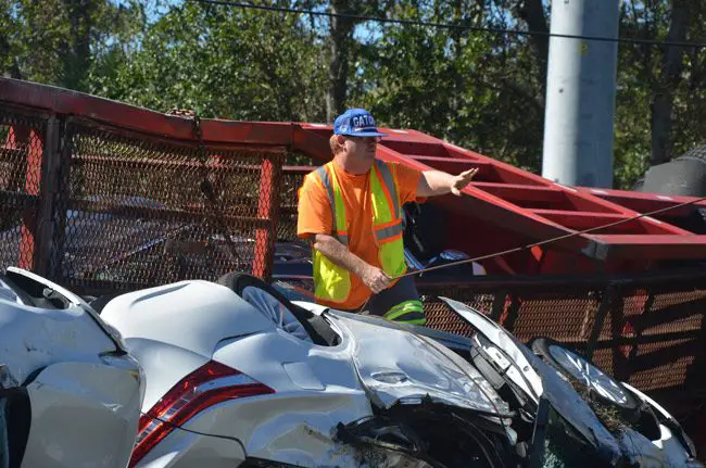 John Rogers is a two-term Bunnell city commissioner, but his day job can get more interesting: he owns John's Towing in Bunnell, and often finds himself untangling wrecks, as he did Saturday, after a car transport overturned on Old Kings Road. (© FlaglerLive)