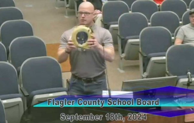 "This little piece of crap here, it looks like it's been drug around in the back of a dump truck, saved my daughter's life," Shawn Sema, impact director with Who We Play For, told the Flagler County School Board Tuesday evening as he described how he'd provided thousands of physicals to student-athletes that, without an ECG, could not prevent what happened to his daughter, when she collapsed at school in 2016. (© FlaglerLive via Flagler Schools YouTube)