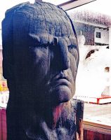 The face of Crazy Horse carved in 1952 out of Ponderosa Pine by Korczak Ziolkowski. The white sculpture visible through the rain-streaked window pane is a scale model of the mountain sculpture of Crazy Horse.