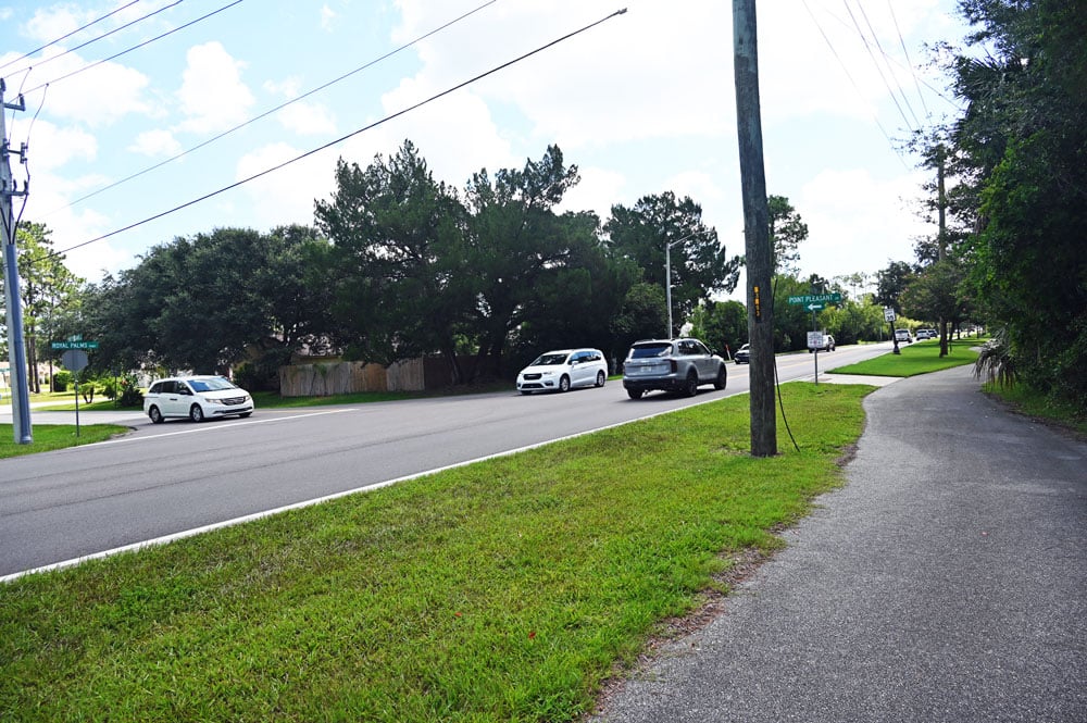 There is a crossing point from the footpath at Royal Palms Parkway and Point Pleasant, but no crosswalk and no signs cautioning for pedestrian safety, though the crossing point is frequently used by P-Section residents, on foot and on bicycles. (© FlaglerLive)
