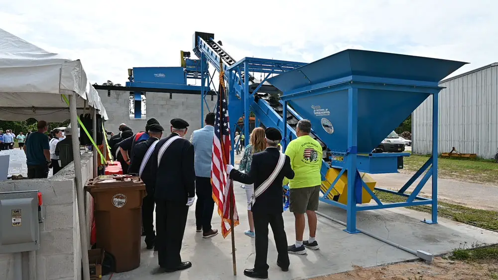 It was all pomp and crushed glass at a demonstration of Flagler Beach's "big Blue" glass-recycling machine this morning on the grounds of the city's sanitation department. (© FlaglerLive)