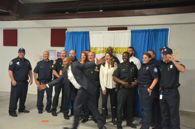 Belle Terre Principal Terence Culver photobombs the dozen-odd first responders, among them Sheriff Rick Staly, and Palm Coast Mayor Milissa Holland and School Board member Colleen Conklin, toward the end of the read-in. Click on the image for larger view. (© FlaglerLive)