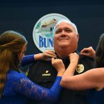Bunnell Police Chief Dave Brannon getting his stars pinned on his collar by his wife and daughter at Monday's Bunnell City Commission meeting. (© FlaglerLive)