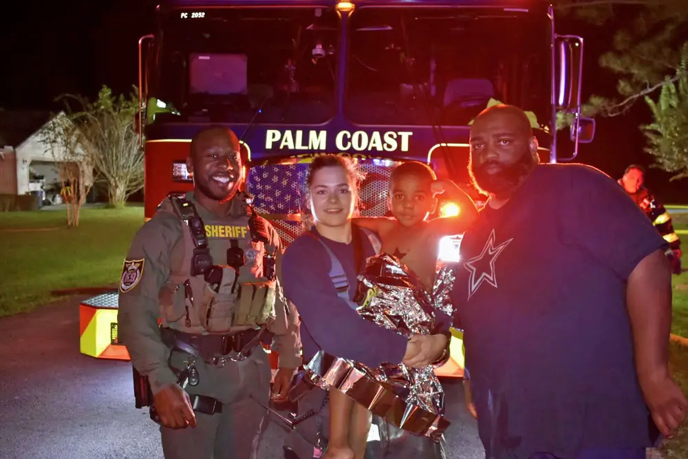 From left, Flagler County Sheriff's Deputy Marcus Dawson, Palm Coast Fire Department Firefighter-Paramedic Kalin Graham, the 3-year-old boy, and his father, Kevin Farris. (FCSO)