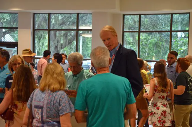Dennis McDonald, usually the tallest man in the room, speaking to a constituent at an event for political candidates earlier this summer. (© FlaglerLive)