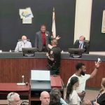 A flagler County Sheriff's deputy intervened as Commissioner Joe Mullins was insulting fellow-Commissioner Greg Hansen, to the right of Mullins on the dais, Wednesday during a commission meeting. Mullins later wanted to lodge a complaint against a deputy even as he spoke from the dais about the importance of supporting law enforcement. (© FlaglerLive via YouTube)